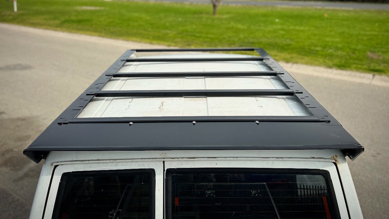 This is an image of a black Tier One Metalworks roof rack fitted on a white 4x4 vehicle roof