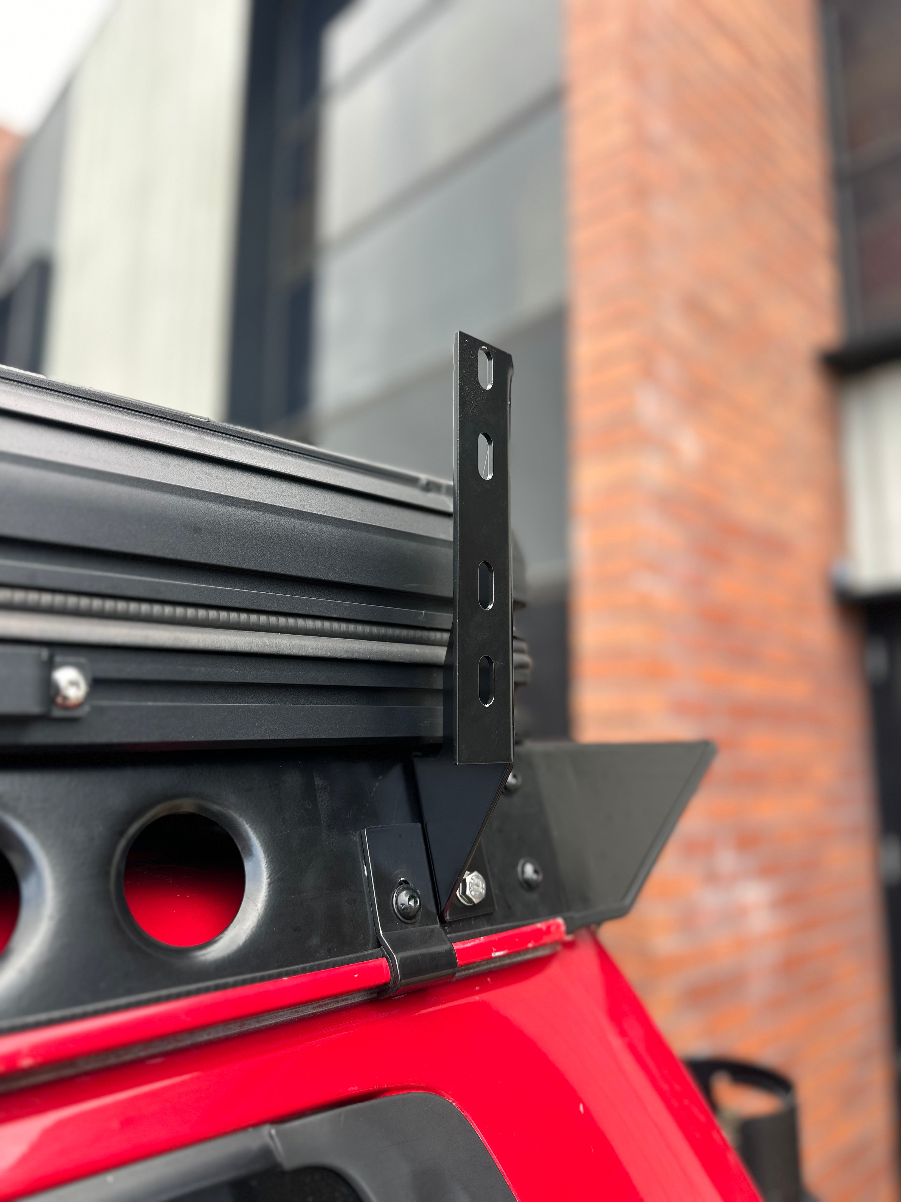 This is an image of a black metal bracket on a red vehicle fitted with Tier One Metalworks Roof Rack and Rails