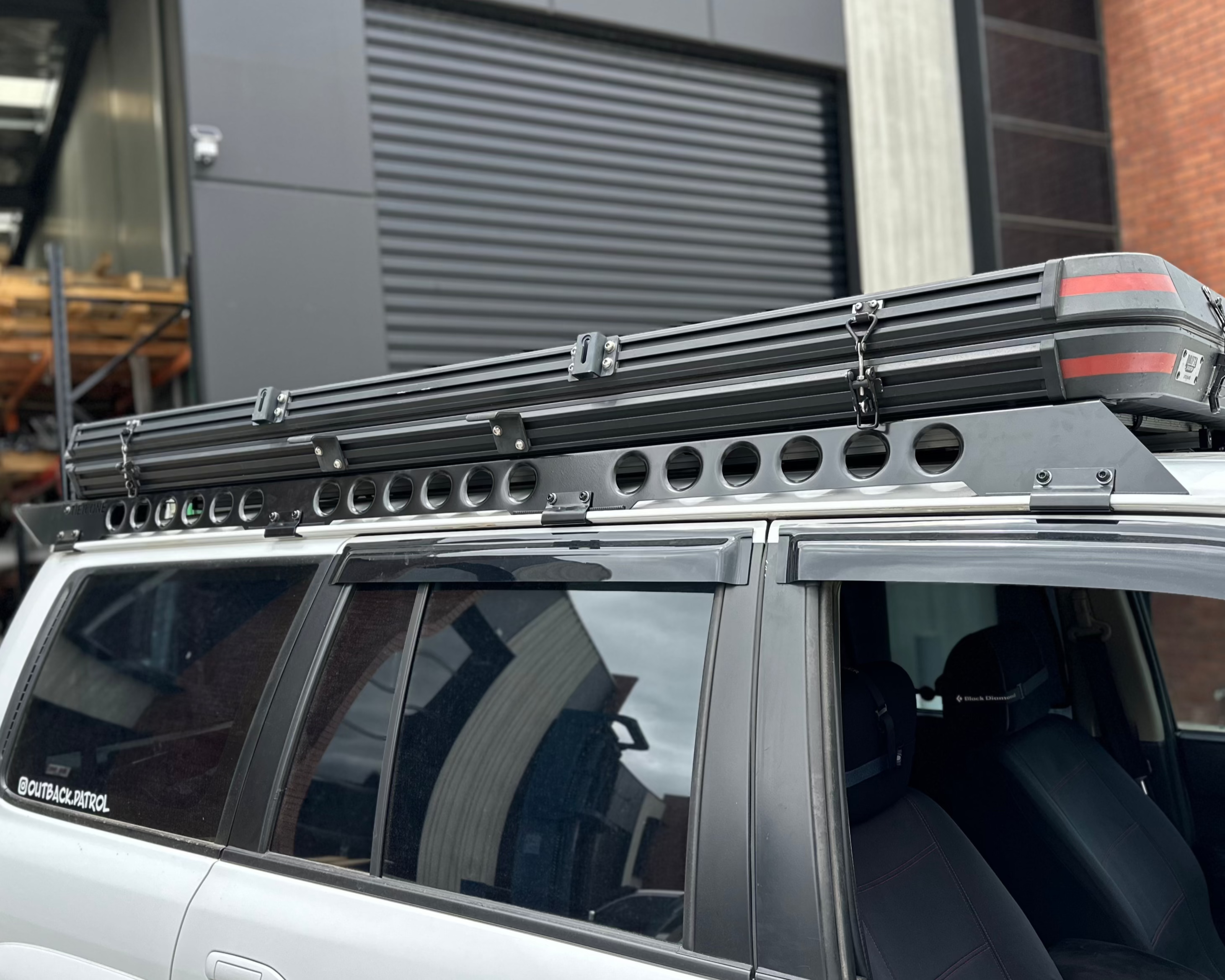 This is an image of a silver 4WD with Tier One Metalworks black aluminium roof rack and rails mounted on top