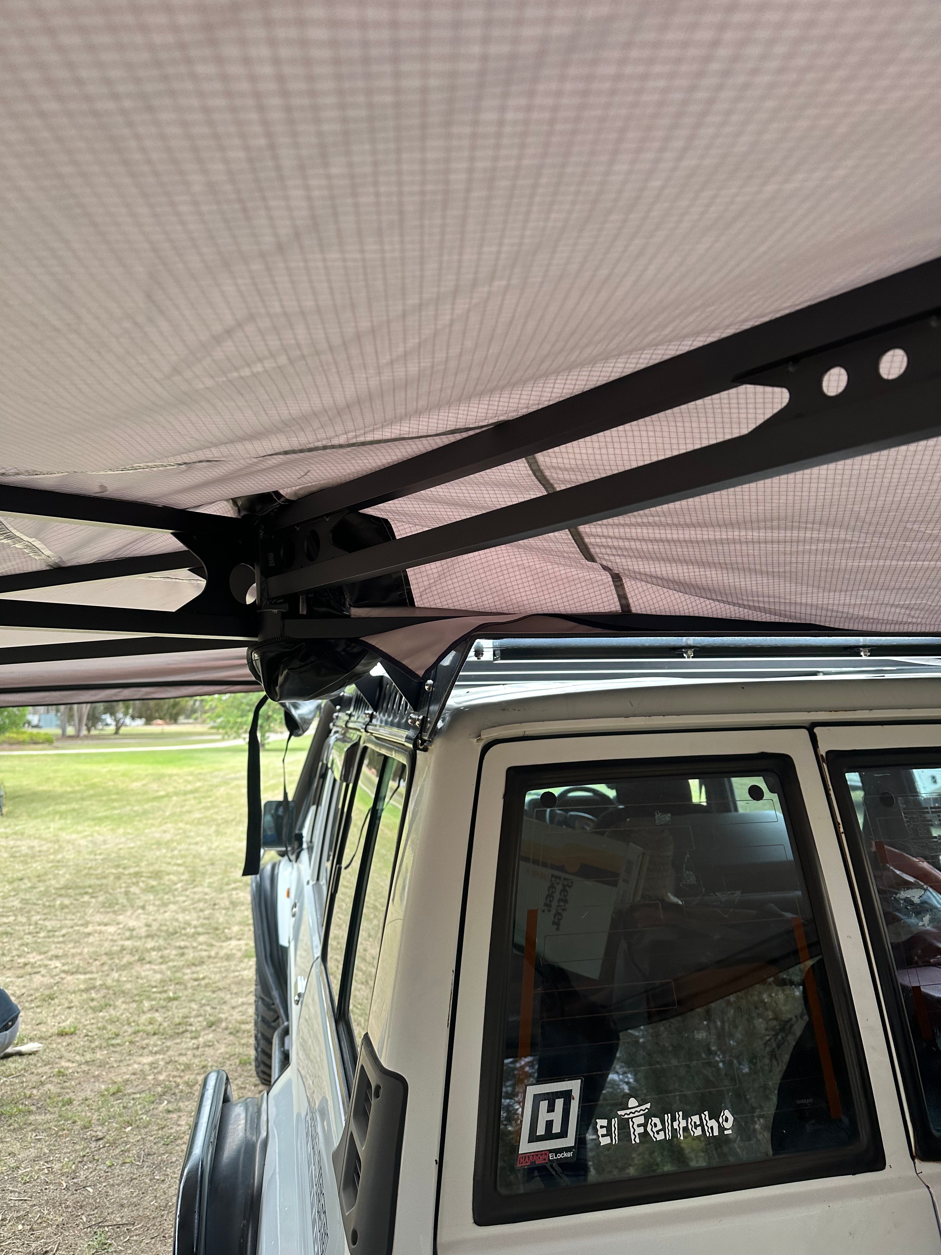 This is an image of a white 4WD with a black metal awning frame attached, showcasing Tier One Metalworks Roof Racks & Rails