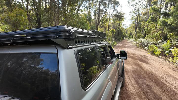 This is an image of a silver 4WD with Tier One Metalworks Roof Rack driving on a bush dirt road in Australia
