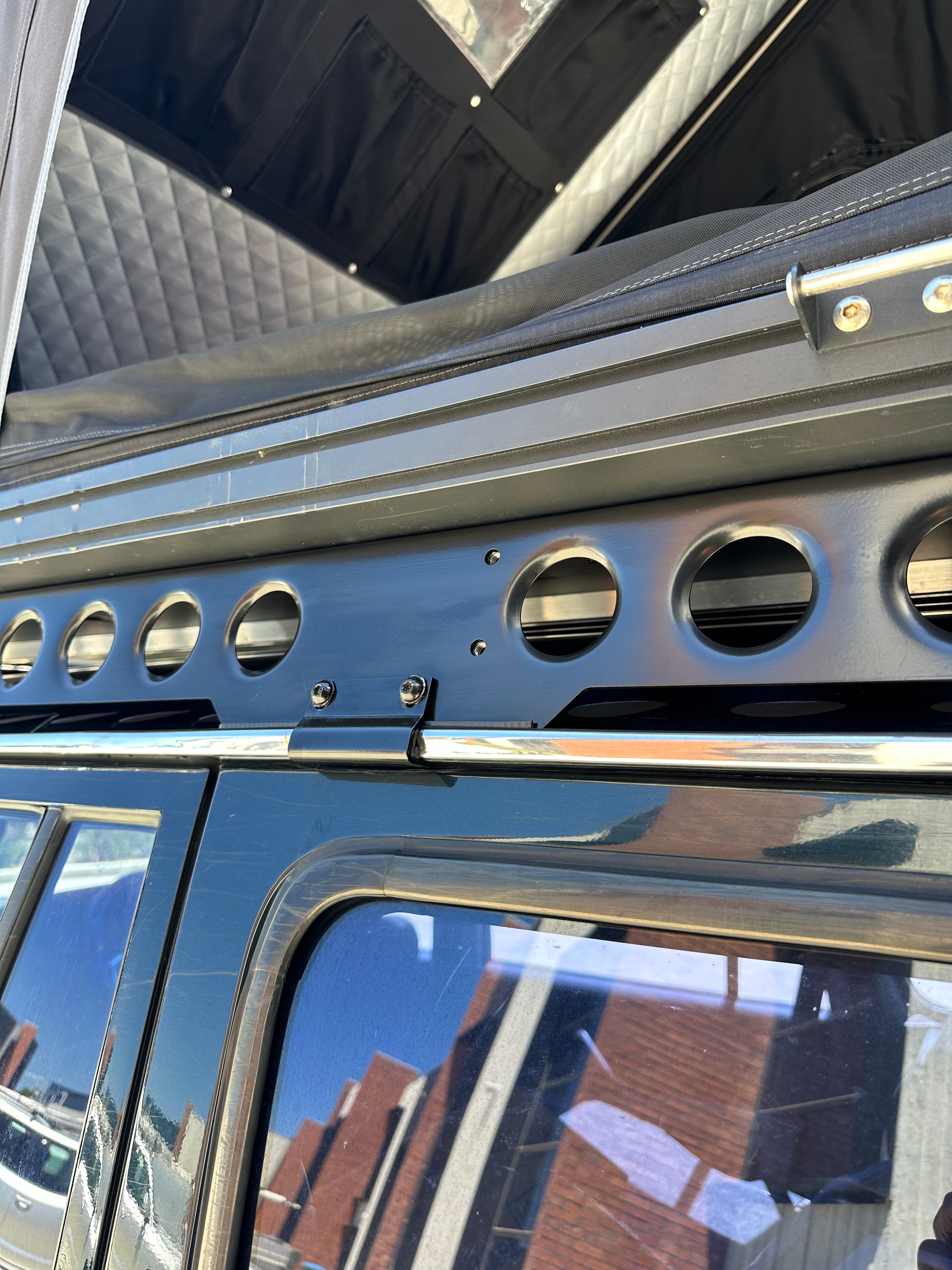 This is an image of a black vehicle with a Tier One Metalworks Roof Rack & Rails and a rooftop tent visible on top.