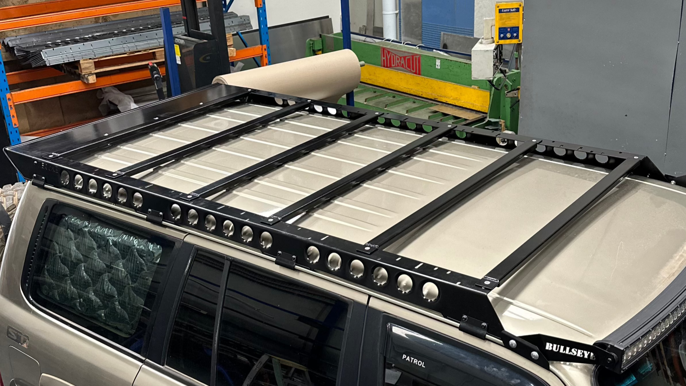 This is an image of a black Bullseye roof rack mounted on a beige Nissan Patrol with Tier One Metalworks Roof Racks & Rails