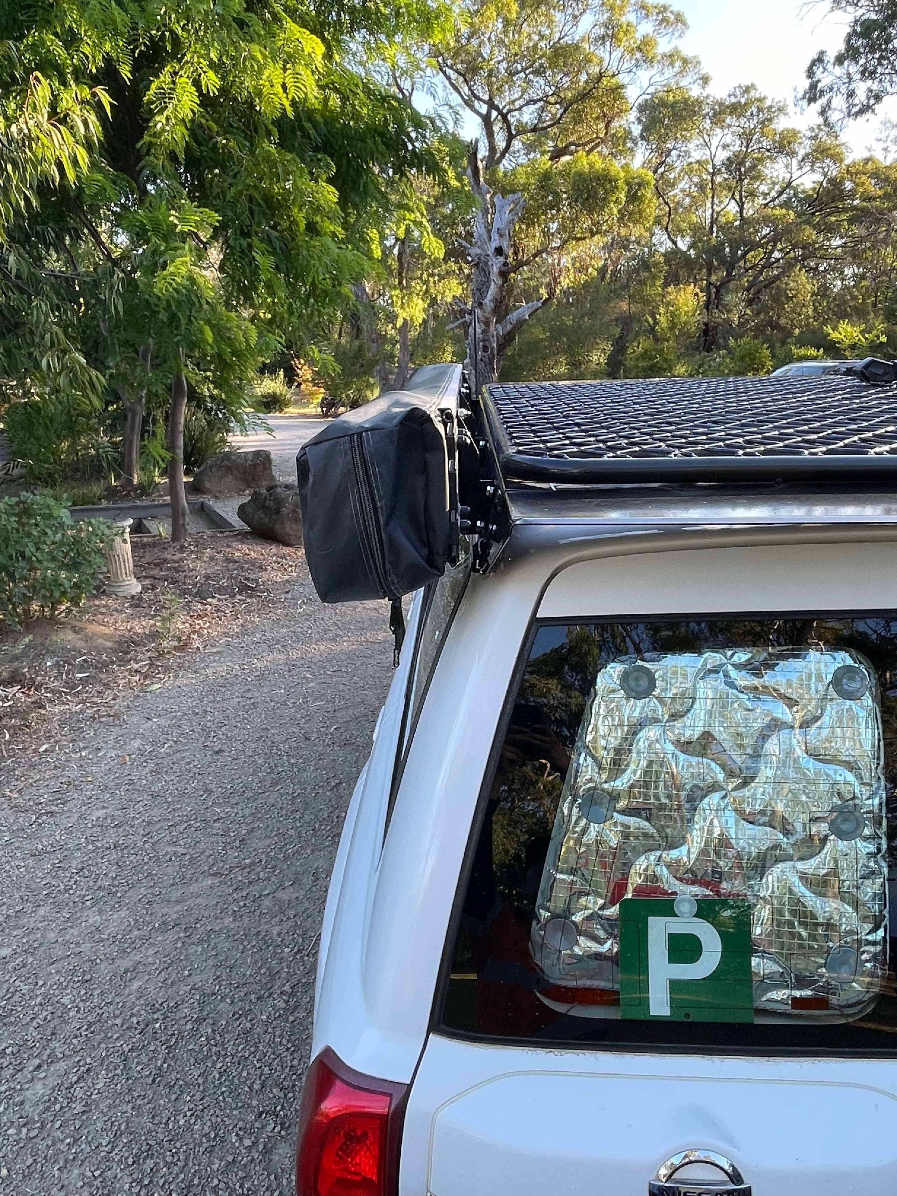 This is an image of a white Nissan Patrol with Tier One Metalworks roof racks and Rails in an outdoor bush setting.