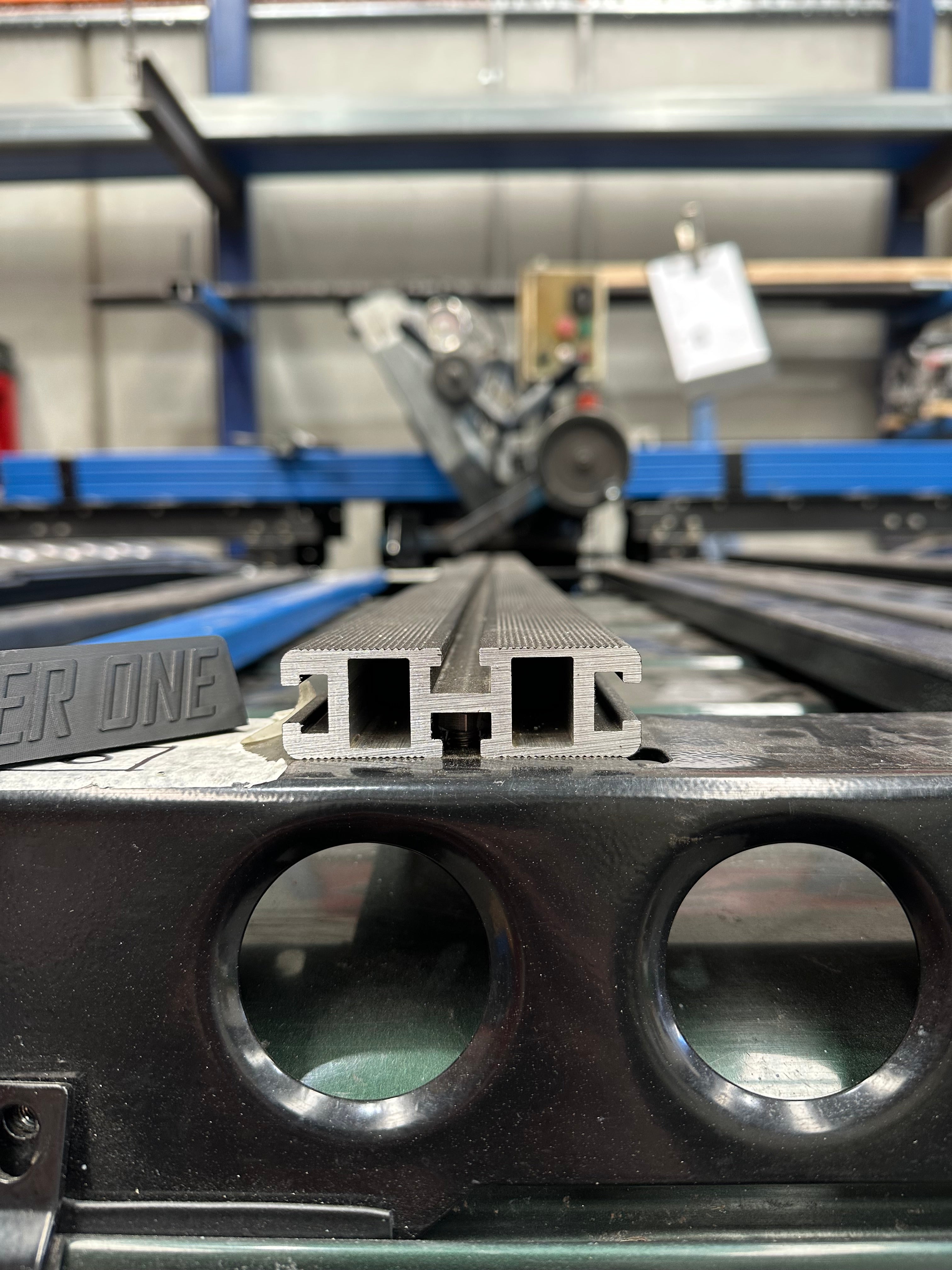 This is an image of Tier One Metalworks aluminium roof rack rail profile on a black metal frame in a workshop
