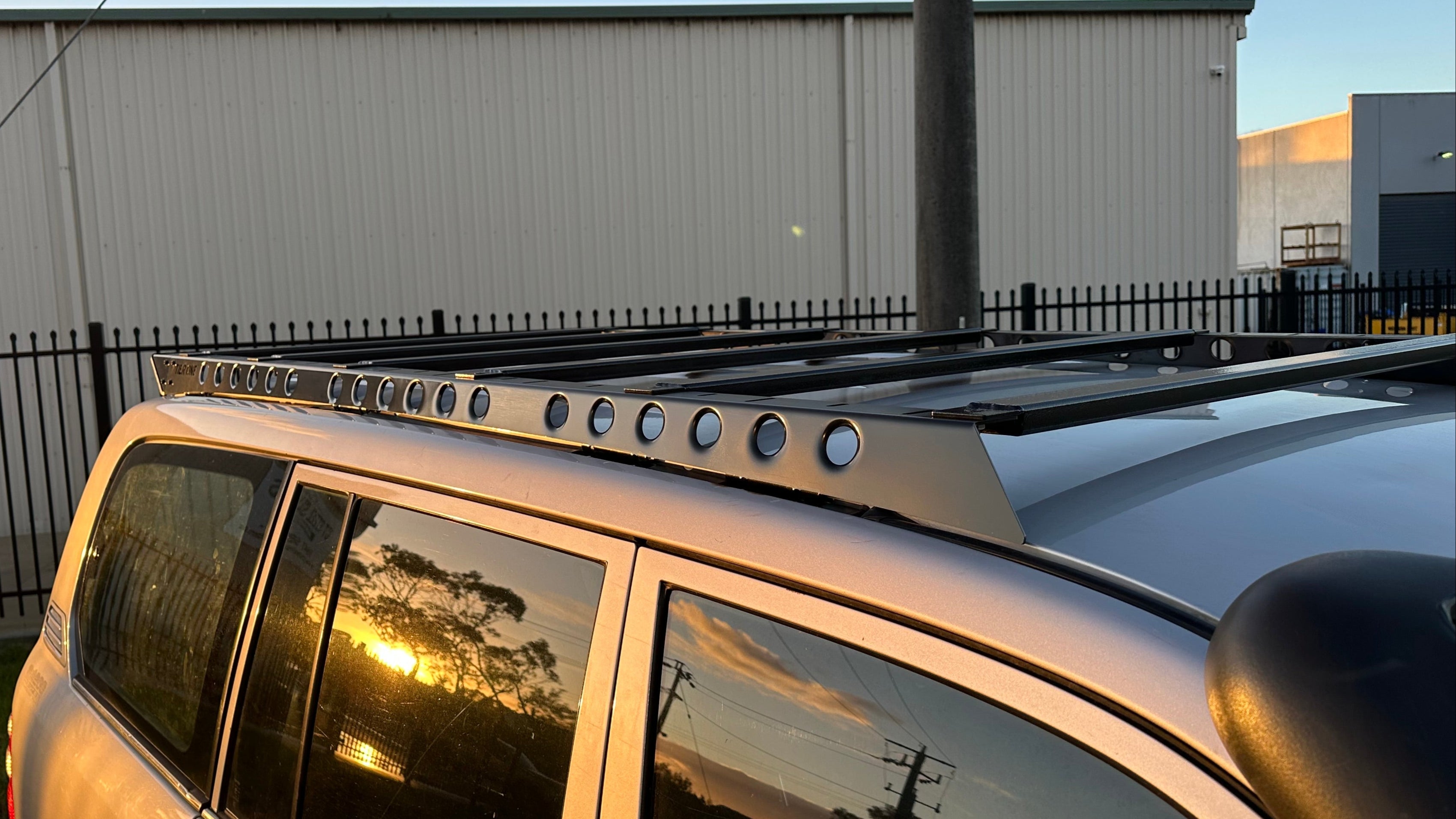 This is an image of a silver 4x4 with Tier One Metalworks Roof Racks & Rails at sunset outdoors