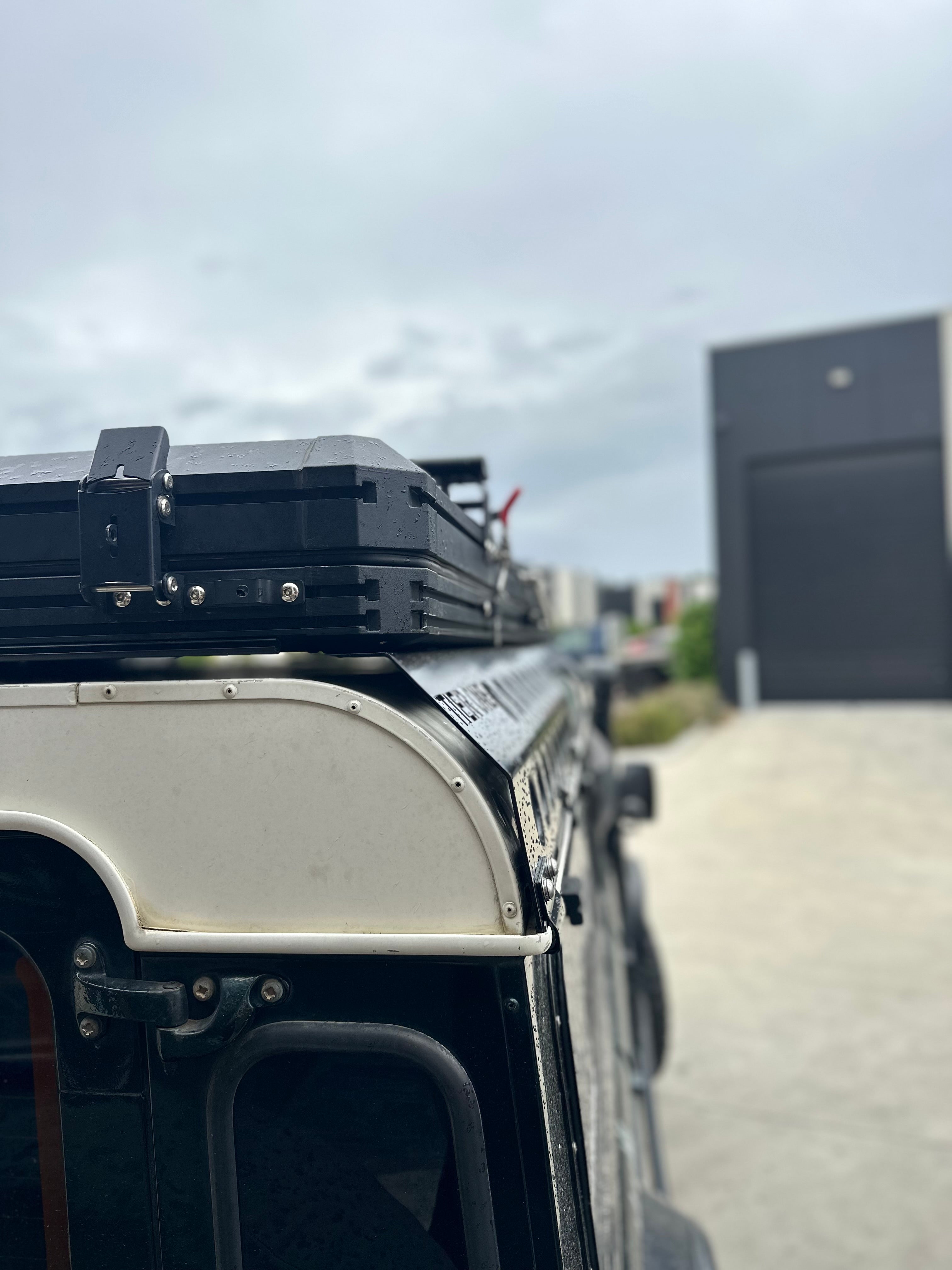 This is an image of a black roof rack mounted on a white roof of a 4x4 vehicle by Tier One Metalworks