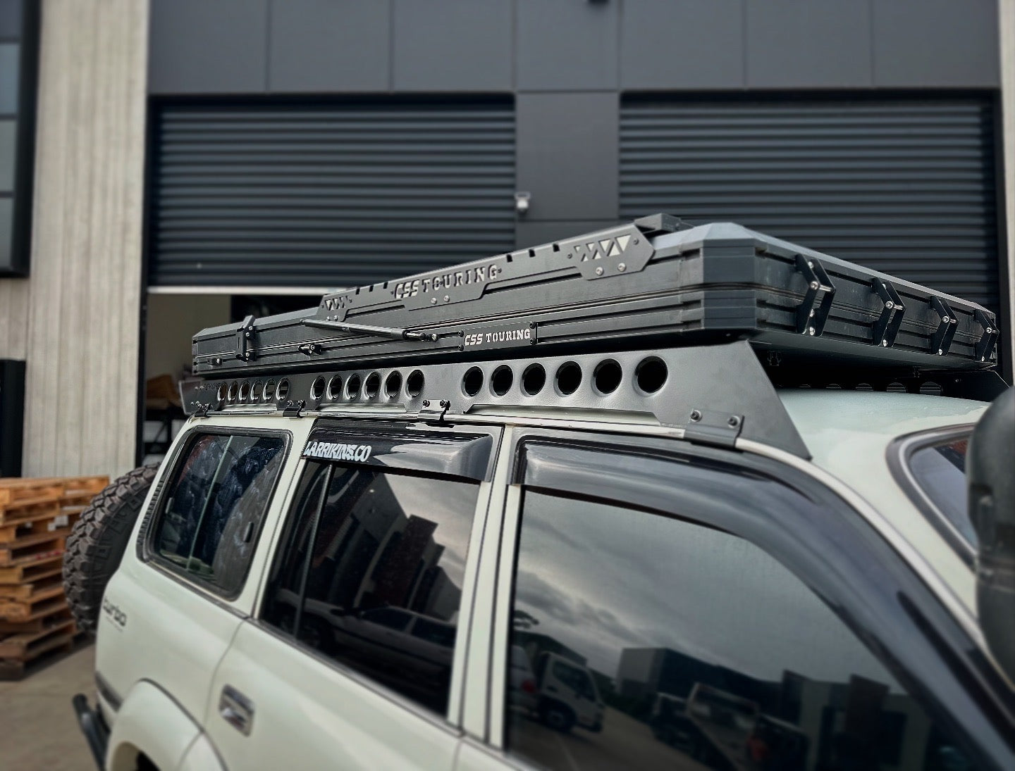 This is an image of a white 4WD with a CSS Touring rooftop tent mounted on a Tier One Metalworks roof rack and rails