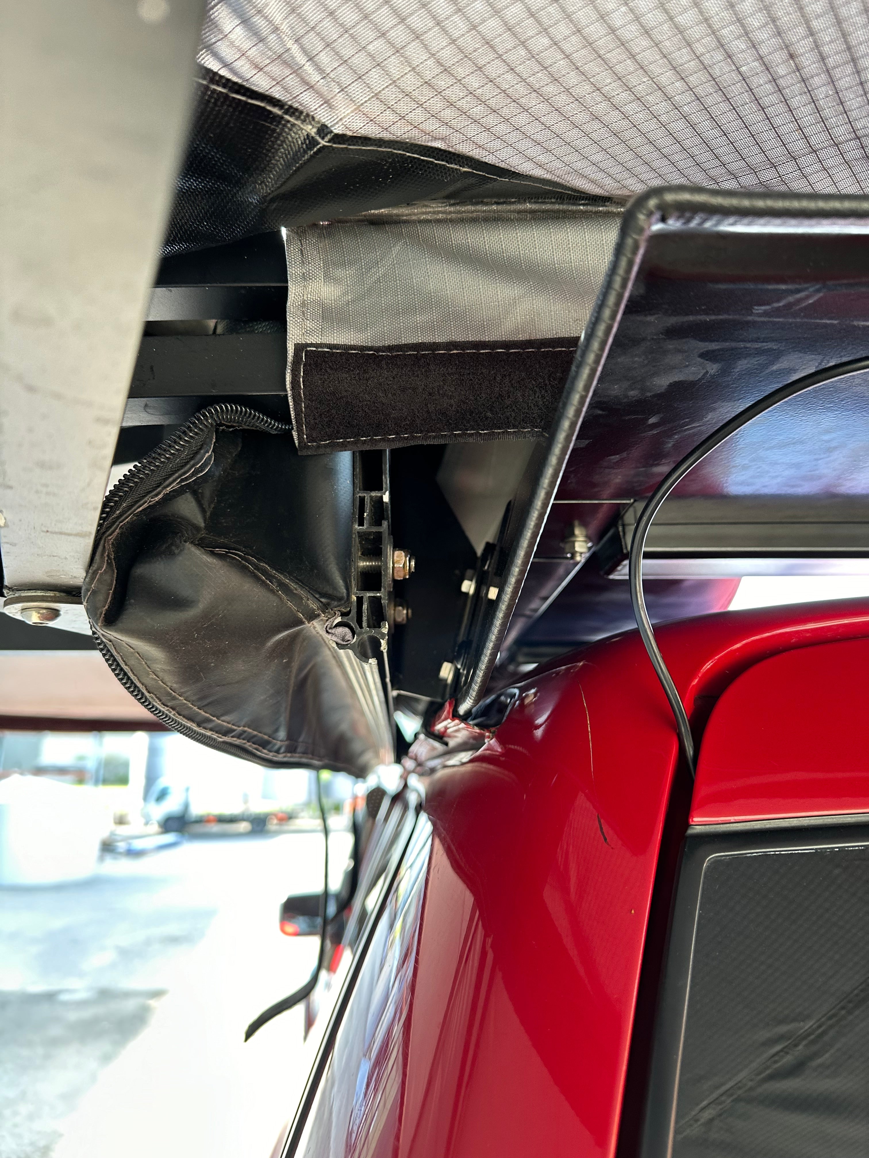 This is an image of a close-up of a red 4x4 vehicle fitted with a Tier One Metalworks Roof Rack and associated awning rails