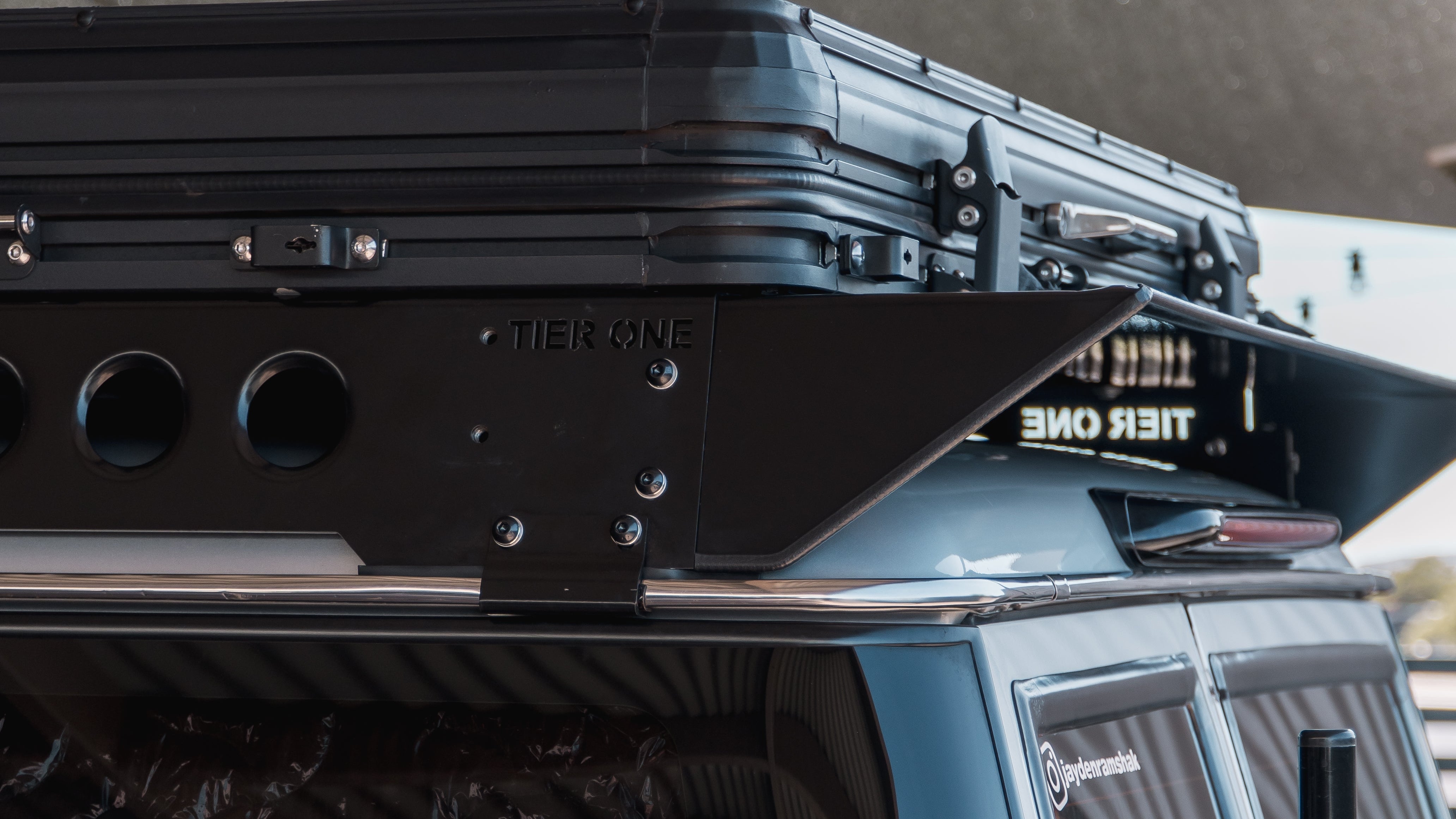 This is an image of a black Tier One Metalworks Roof Rack on a blue 4WD vehicle under shade