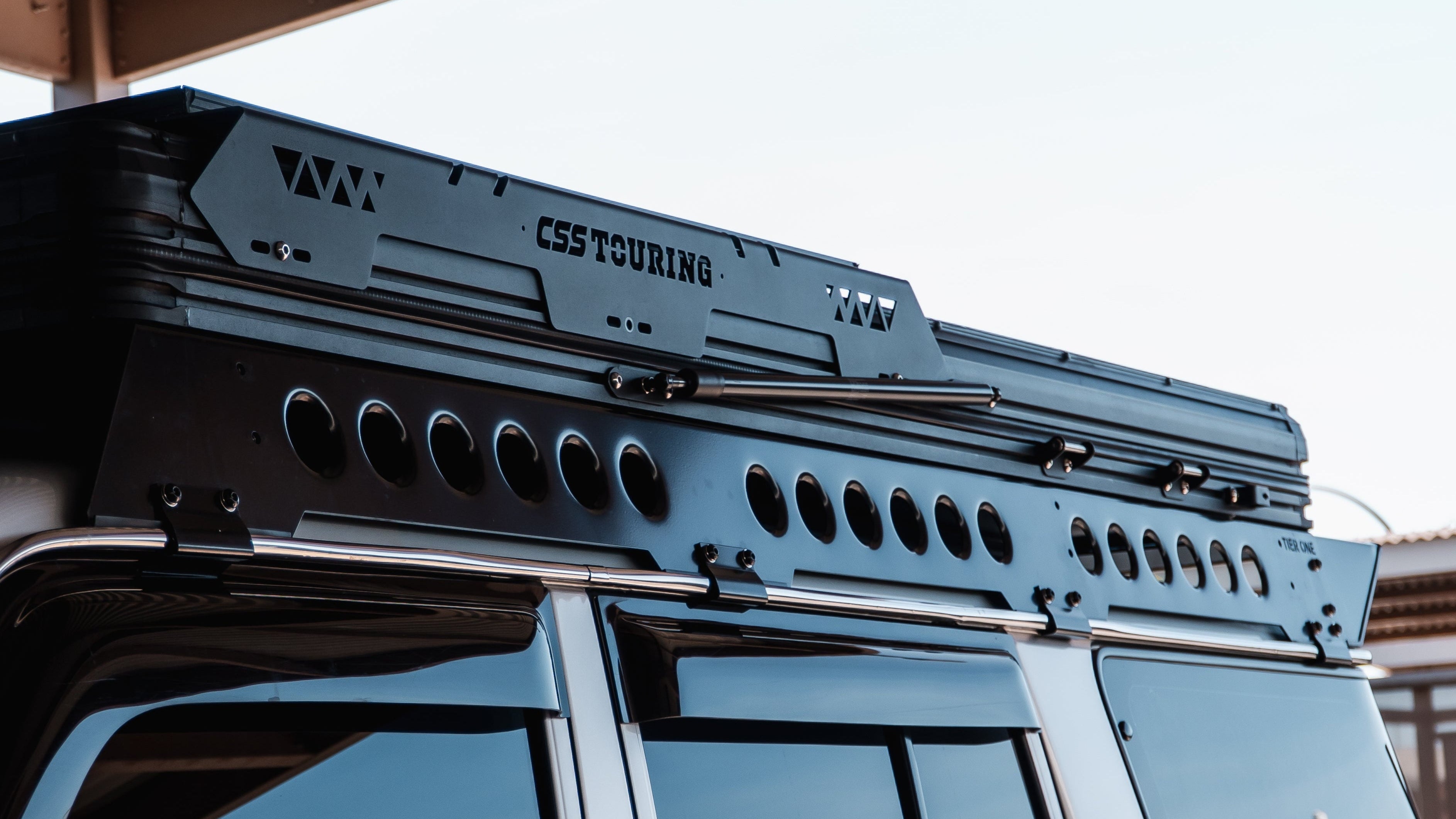 This is an image of a black CSS Touring rooftop tent mounted on a Tier One Metalworks black roof rack and rails on a 4x4 vehicle