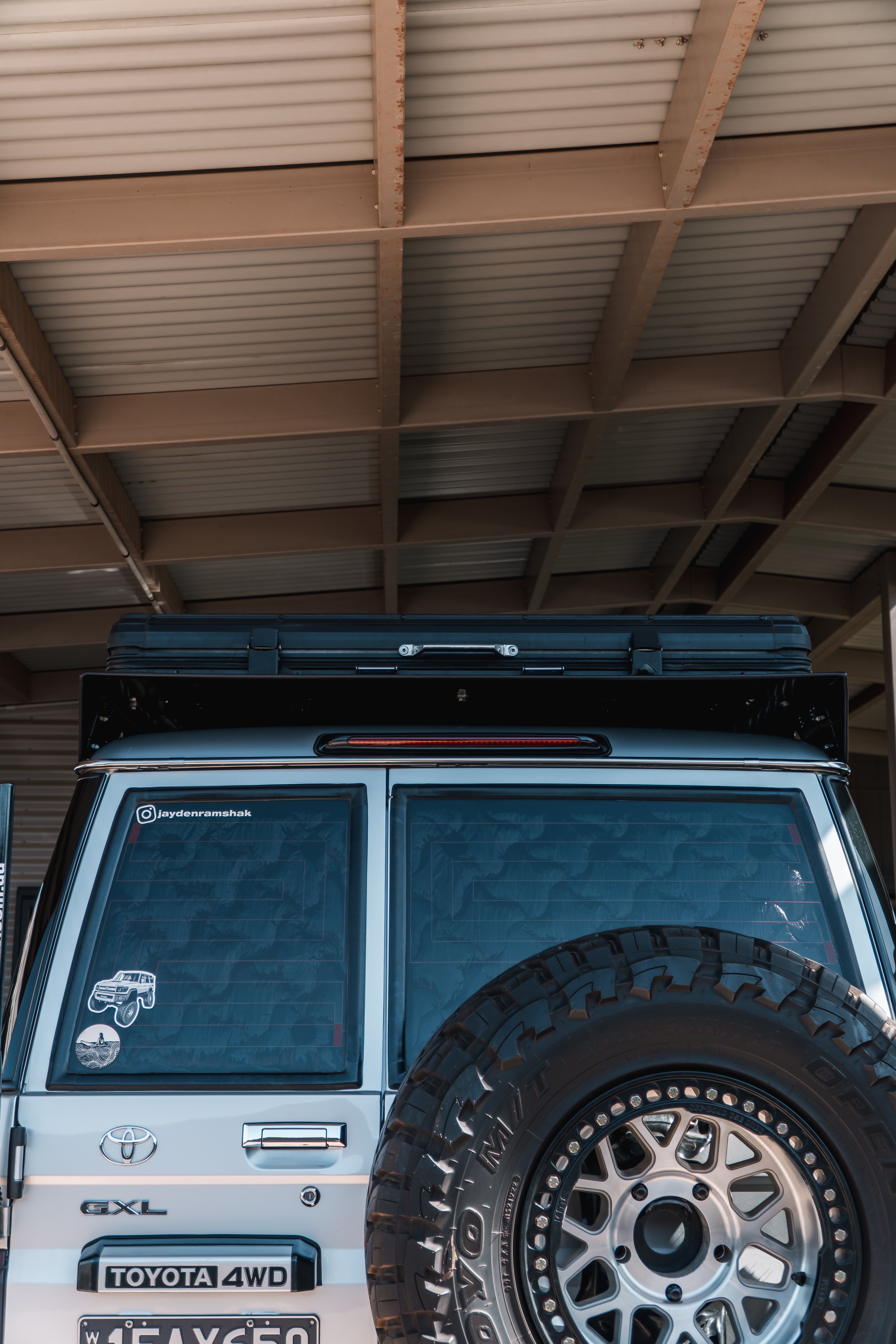 This is an image of rear of silver Toyota GXL 4WD with Tier One Metalworks roof rack and large offroad tyre