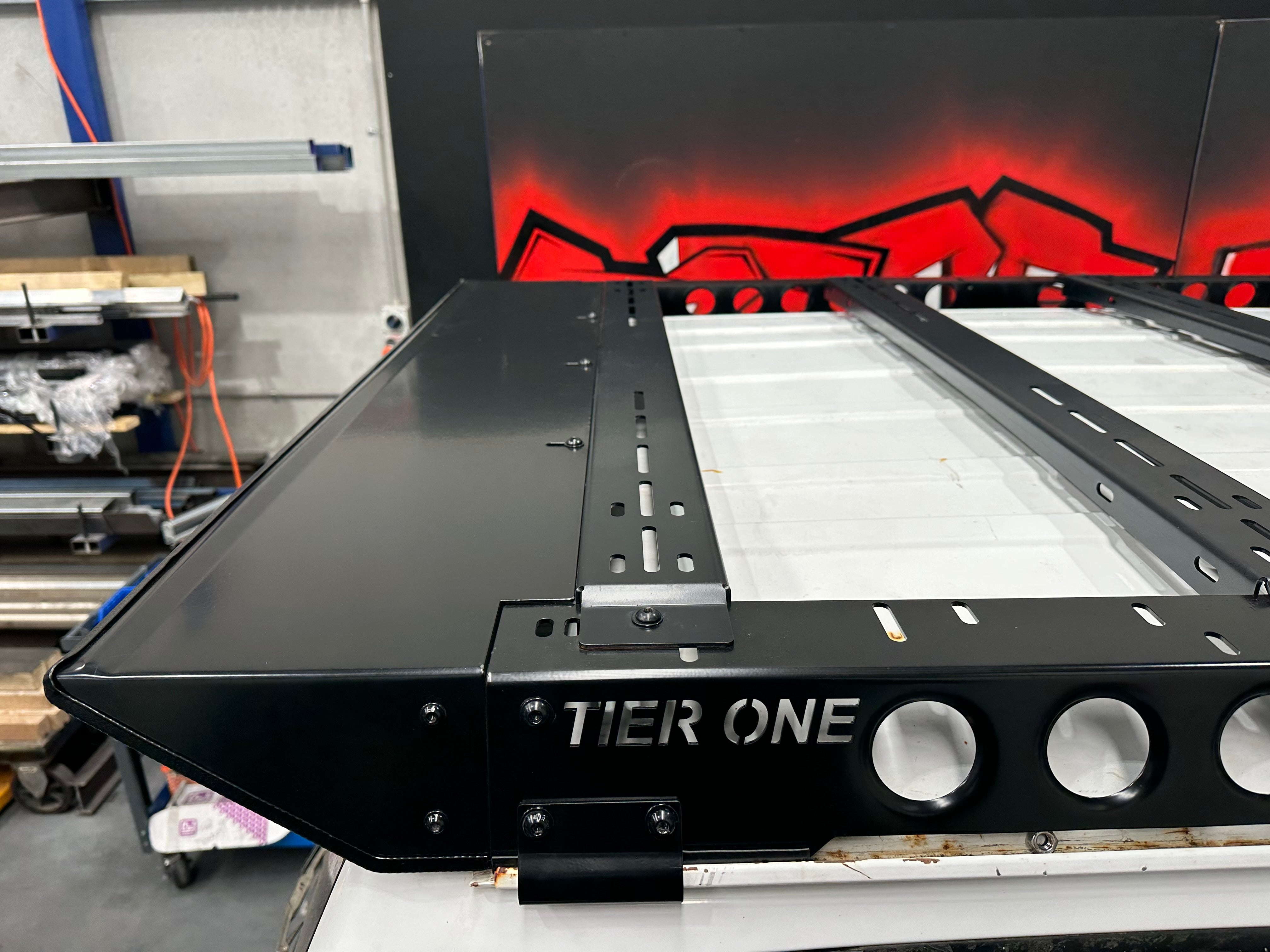 This is an image of a Tier One Metalworks black steel roof rack in a workshop setting