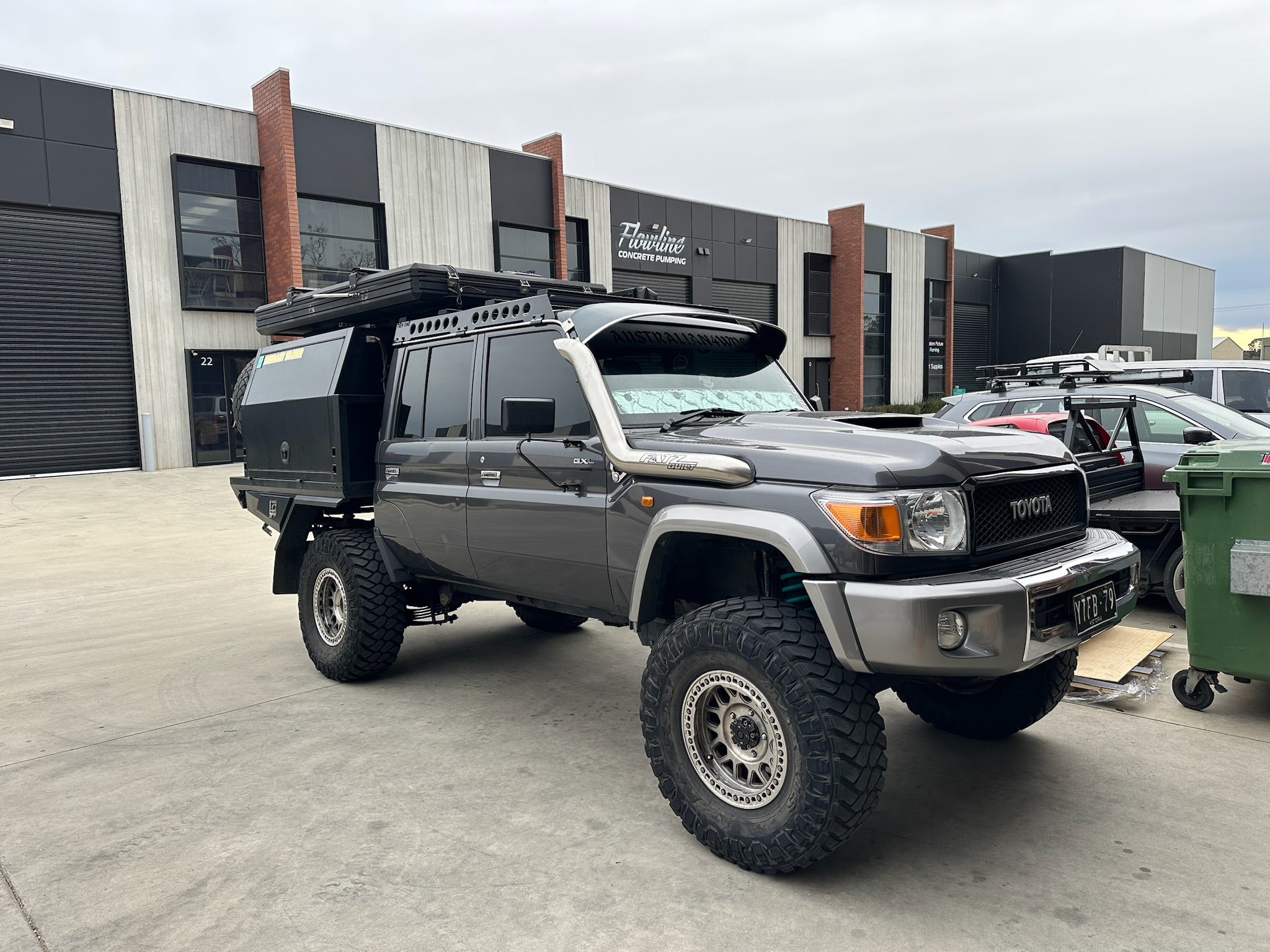 This is an image of a grey Toyota Land Cruiser 70 Series with custom 4WD roof rack and rails by Tier One Metalworks in an industrial setting