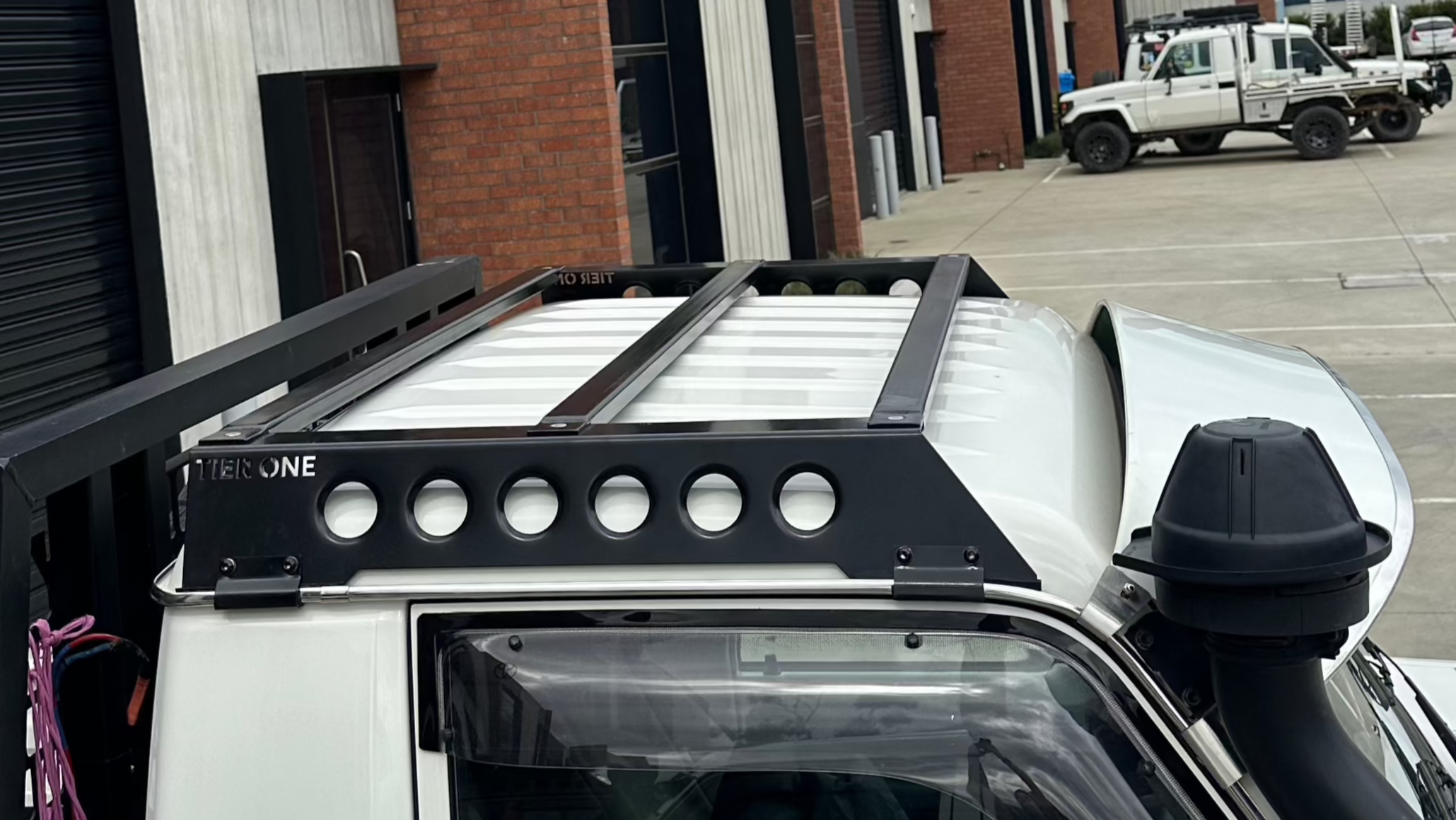 This is an image of a black Tier One Metalworks Roof Rack fitted on a white Toyota Landcruiser 79 Series single cab with a snorkel