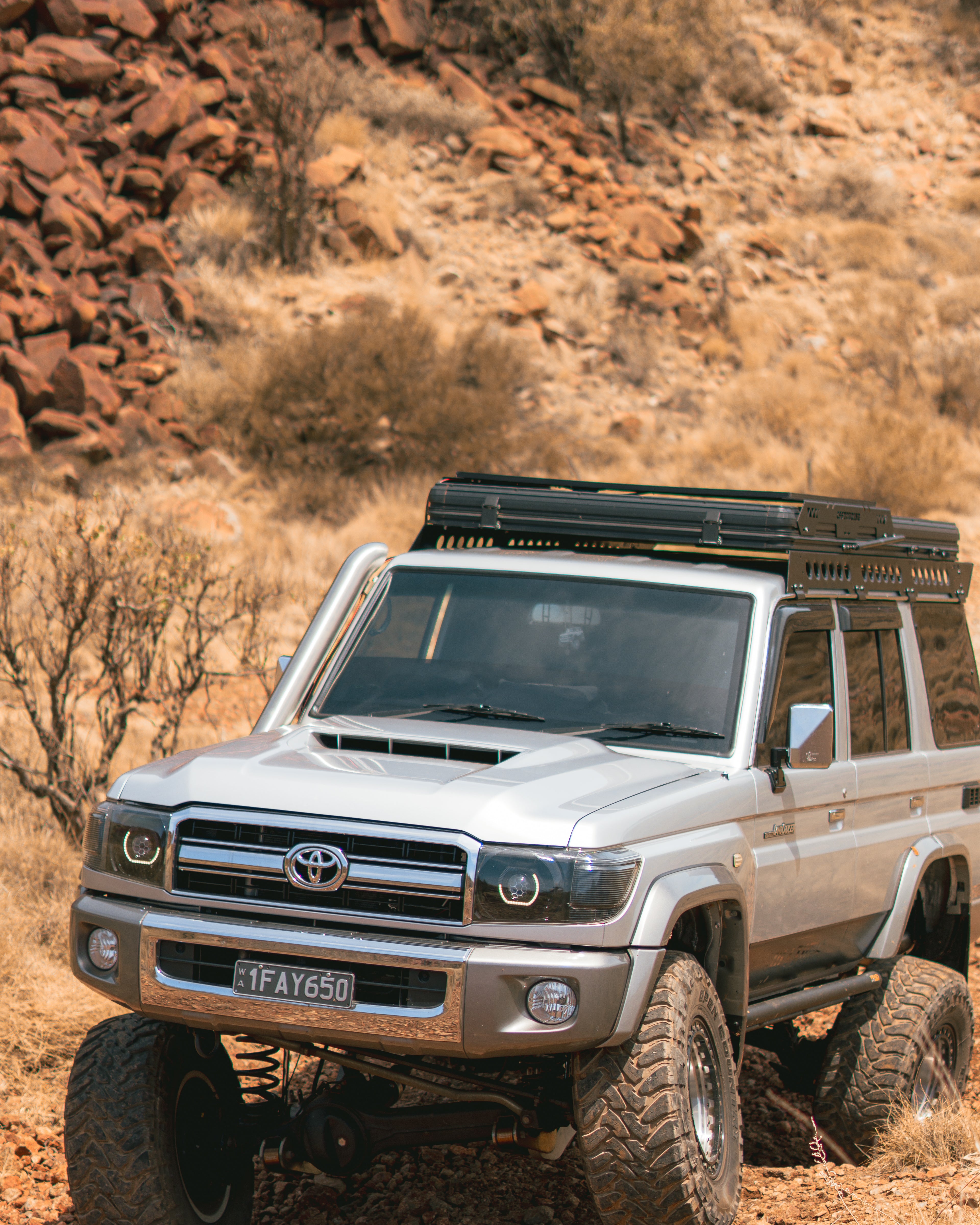 This is an image of a Toyota Landcruiser 76 Series driving through outback Australia featuring the Tier One Metalworks Roof Rack Rail Sides and Rear Wing