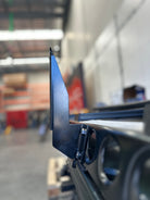 This is an image of a black metal bracket attachment on a 4WD roof rack rail in an industrial workshop, by Tier One Metalworks