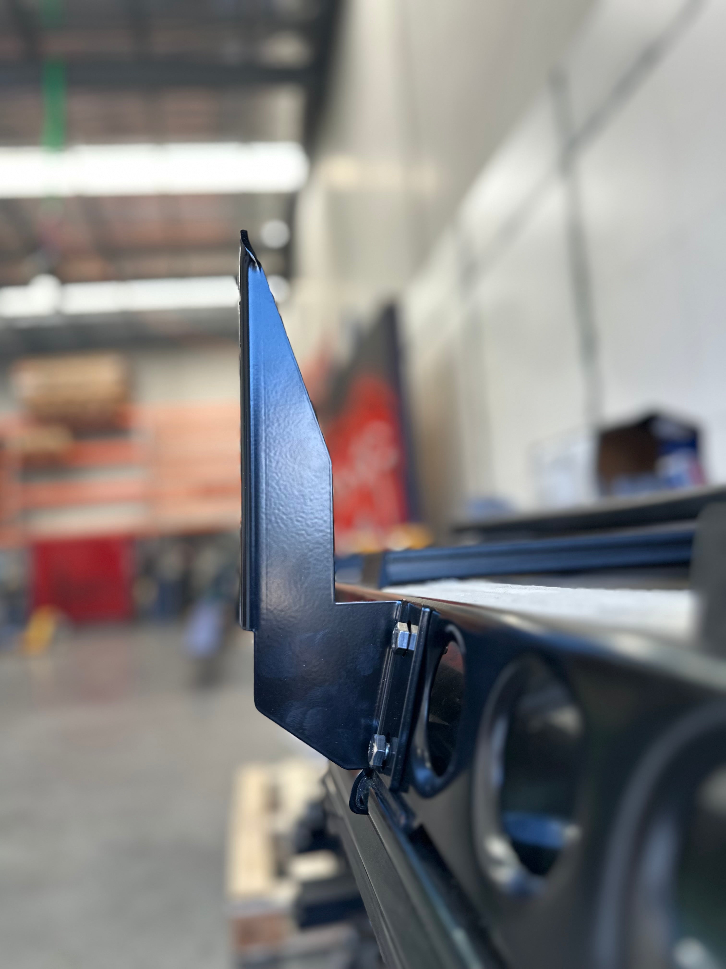 This is an image of a black metal bracket attachment on a 4WD roof rack rail in an industrial workshop, by Tier One Metalworks