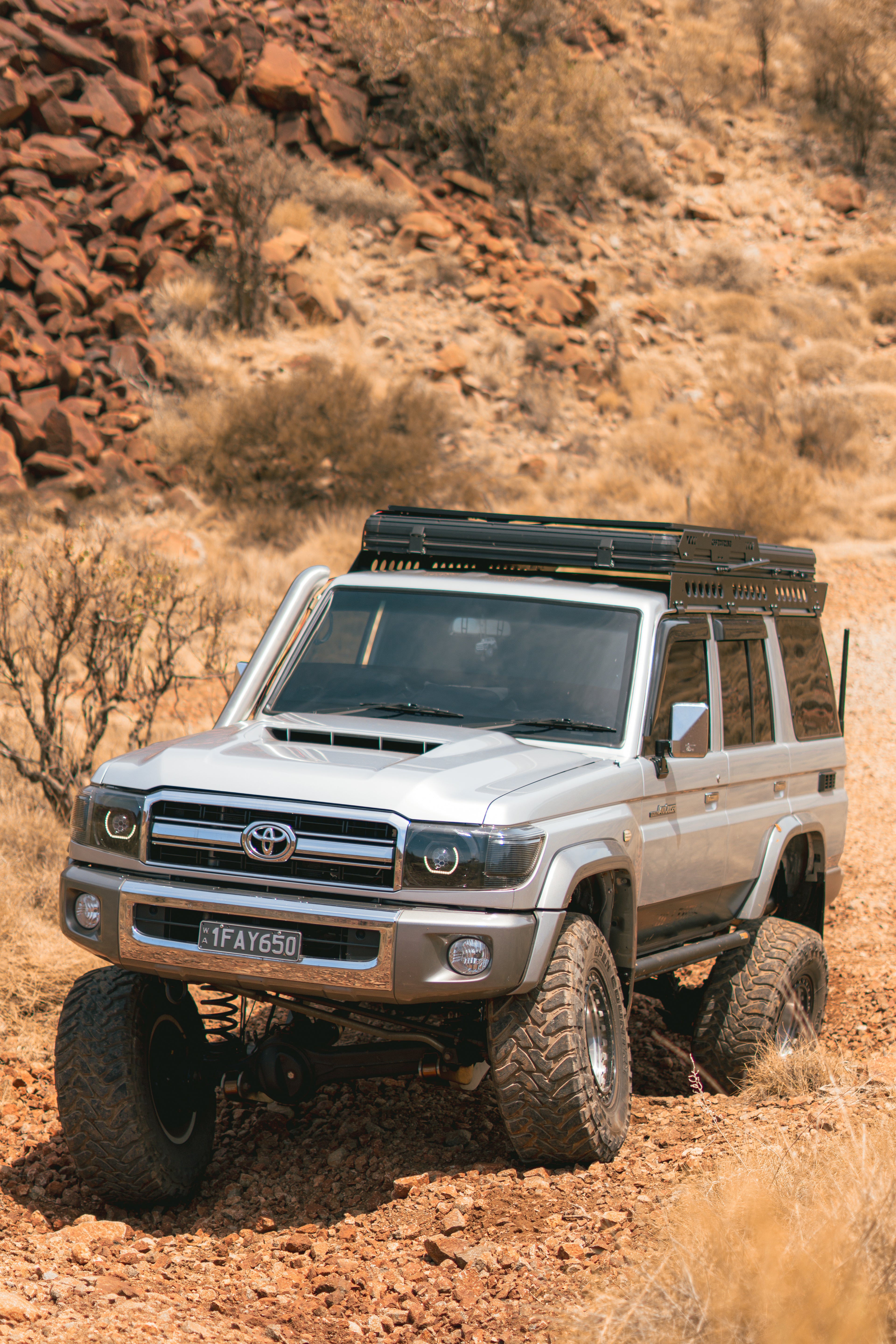 This is an image of a Toyota Landcruiser 76 Series driving through outback Australia featuring the Tier One Metalworks Roof Rack Rail Sides and Rear Wing