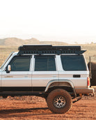 This is an image of the side profile of a Toyota Landcruiser 76 Series driving through outback Australia featuring the Tier One Metalworks Roof Rack Rail Sides and Rear Wing